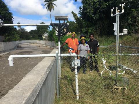A photo showing people next to a 3D-PAWS unit and stream gauge.